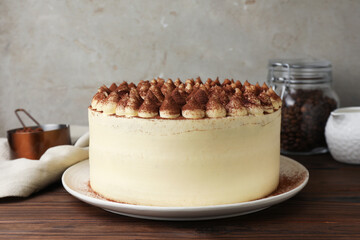 Delicious tiramisu cake with cocoa powder on wooden table