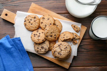 Delicious chocolate chip cookies and milk on wooden table, flat lay