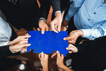 Top view multiethnic business people holding jigsaw pieces and merge them together as effective...