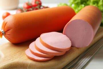 Board with tasty boiled sausages on white table, closeup