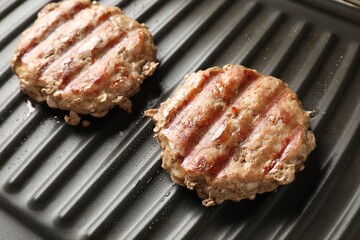 Delicious hamburger patties cooking on electric grill, closeup
