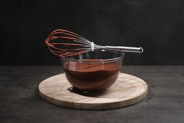 Bowl of chocolate cream and whisk on gray table