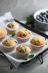 Delicious sweet muffins with blueberries and mint on grey table