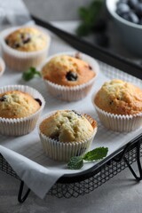 Delicious sweet muffins with blueberries and mint on grey table