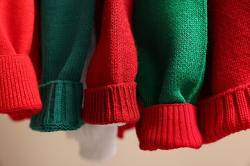Different Christmas sweaters hanging on rack, closeup