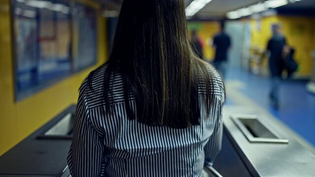 Young beautiful hispanic woman checking ticket on subway toll gate in subway station of Madrid