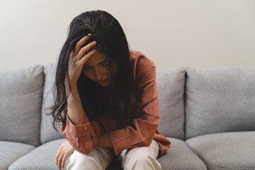 Stressed female feeling depressed and lonely on the sofa in the house.