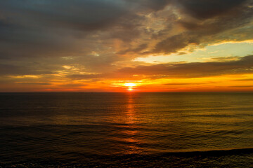 During early morning hours, sun rises over waves ocean