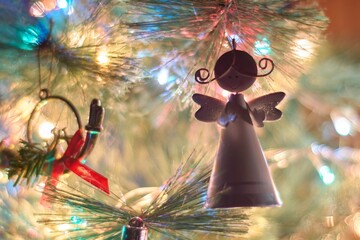 Close up of angel ornament hanging on Christmas tree on blurred background with Christmas lights....