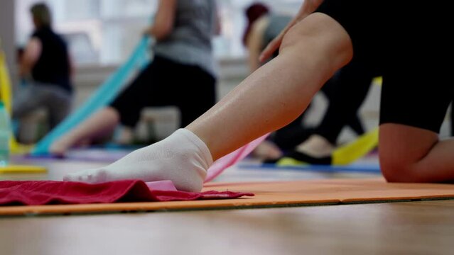 Women's legs in yoga classes. Sports activities for women. Static picture, close-up. Developing stretching with ropes.