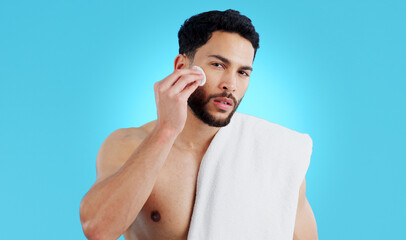 Skincare, portrait and man with cotton pad in studio for luxury, grooming or wellness on blue background. Face, hands and male model with facial swab for cleaning, cosmetics or after shower beauty
