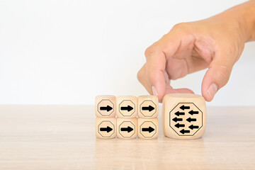 Hand chooses arrow icon point to the opposite side on cube wooden block stack pyramid concept of adaptation challenge change transformation business plan and choice the way forward goal to growth
