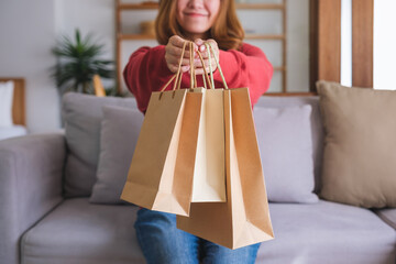 Closeup image of a young woman holding and showing shopping bags at home