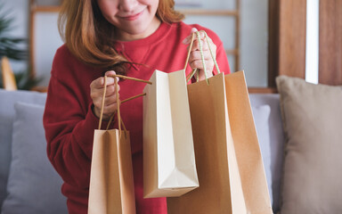 Closeup image of a young woman holding and opening shopping bags at home