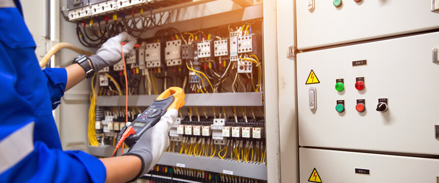 Electricity and electrical maintenance service. Engineer hand checking electric current voltage at circuit breaker terminal and cable wiring in main power distribution board AHU starter control panel.