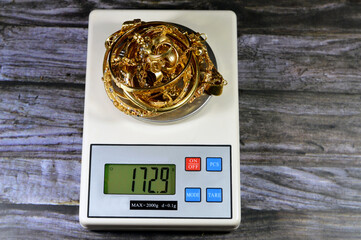 Pile stack of gold on a digital accurate scale in grams, bracelets, rings and gold chains, gold...