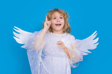 Child angel pointing up, point gesture. Valentine's day. Blonde cute child with angel wings on a...