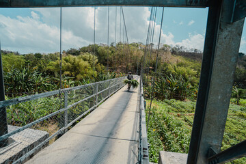 A suspension bridge that can only be used by two-wheeled vehicles and can only be crossed in turns. Villagers are crossing a suspension bridge that divides rivers and ravines in the countryside
