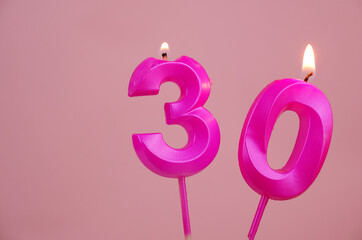 Pink birthday candles burning and melting on pink background. Copy space for text. Number 30.