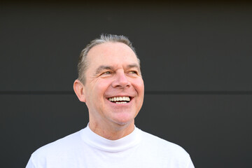 Fototapeta premium A middle aged man in a white turtle neck t shirt giving a very big smile