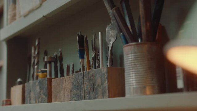 Close-up view of assorted drill bits, chisels and woodworking hand tools on the shelf in workshop
