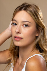 Portrait of caucasian woman wearing natural makeup and beige nail polish on beige background