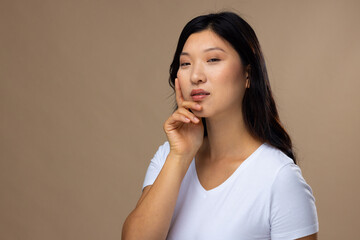 Portrait of asian woman wearing natural makeup and white t-shirt on beige background, copy space