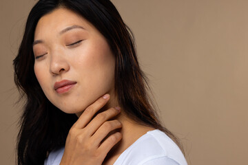 Asian woman wearing natural makeup and white t-shirt on beige background, copy space