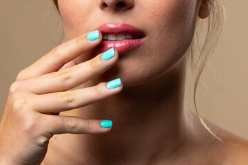 Naklejka premium Caucasian woman wearing natural makeup and blue nail polish on beige background