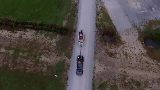 Aerial Top Backward Shot Of Pickup Truck Pulling Boat On Road - Bayou, Louisiana