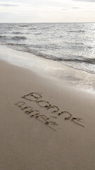 happy new year in french text sign means bonne annee message handwritten in smooth sand with sunrise on coming wave on the beach