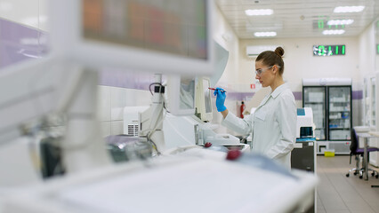 Fototapeta na wymiar A female scientist controls the operation of devices for laboratory research. Modern laboratory technologies. Medical research centrifuge.