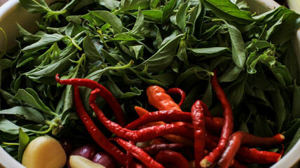 basil leaves, chilies and shallots in a container on the table