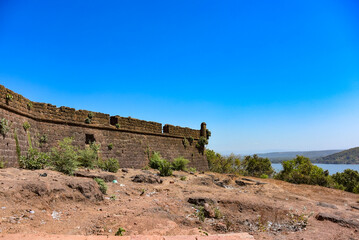 Fortress tower in Fort Chapora. In the background is a view of the beaches of Anjuna and Vagator in the northern part of Goa. The fort rises high above the Chapora River, India. Indian Ocean.