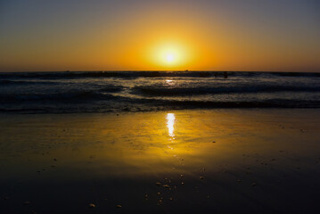 Sunset on Mandrem Beach in Goa, India. Bright and colorful sunset over the Indian Ocean, the Arabian Sea. A tropical beach with yellow sand and a bronze sunset.