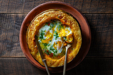 Half a baked pumpkin along with fried eggs on a wooden background, closeup