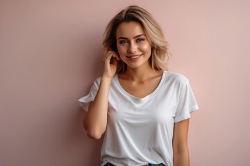 confident beautiful blonde girl in white T-shirt posing on a monotonous pink background