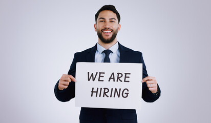 Happy businessman, portrait and hiring sign for opportunity, advertising or marketing against a gray studio background. Man smile with billboard or poster for recruiting, interview or career position