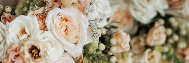 Close-up of peach and white roses in a bouquet on a wooden surface. Concept of expressing love, gratitude, sympathy or congratulations with a beautiful floral gift. Banner with copy space.