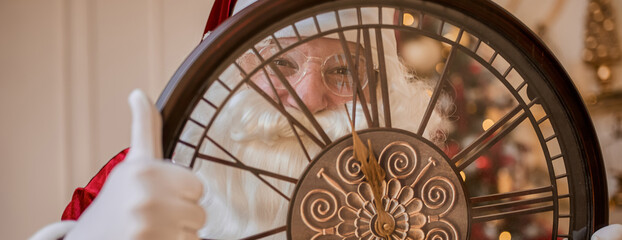 Five minutes to New year or Christmas midnight. Happy Santa Claus shows on the clock