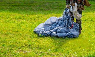 Military Parachuter Standing on the Grass with His Parachute in Switzerland.