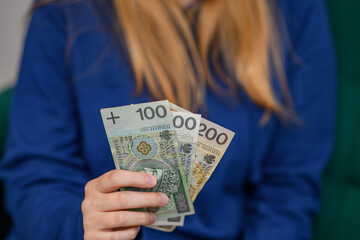 Kobieta trzyma wachlarz polskich banknotów PLN w dłoni - obrazy, fototapety, plakaty