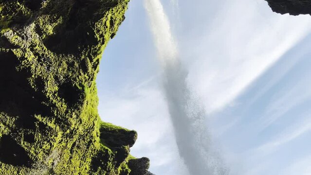Waterfall falling above a cave and crashing into basaltic rocks in Iceland