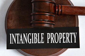 INTANGIBLE PROPERTY- words on a black sheet against the background of a judge's gavel