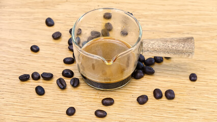 A shot glass with coffee beans on the table.