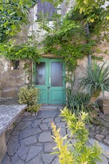Image of an entrance area to an ancient house with climbing plants and a stone resting place
