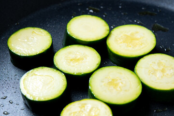 ズッキーニの輪切りをフライパンで焼く調理シーン。
