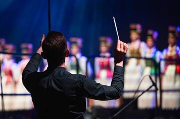 Conductor during classical music concert and dance group in the background