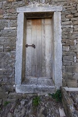 Image of a wooden entrance door to a residential building with an antique façade