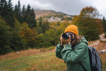 Woman traveler photographer taking photo using camera during autumn trip to mountains - obrazy, fototapety, plakaty